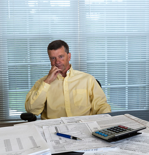 Senior caucasian man weary from preparing tax form 1040 for tax year 2012 with calculator